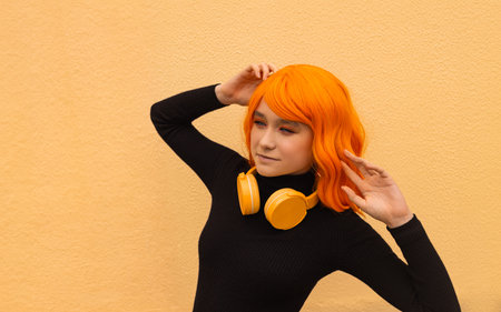 Girl dancer with creative orange hair and hairstyle and headphones. Lifestyle photo. Cosplay on an anime character.の写真素材
