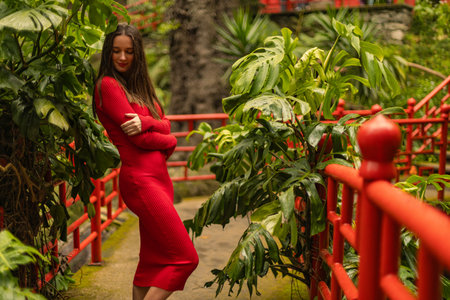 Template for a tourist travel postcard. Woman in the red dress in Monte Palace Tropical Gardens in Madeira, Funchal. Popular tourist botanical park at Madeira island, Portugal.の写真素材