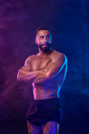 Athlete bodybuilder in neon colors. Fit man posing on black background. Sports concept. Bodybuilding...