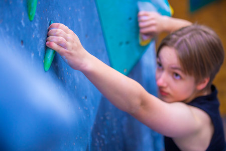 Bouldering climbing athlete woman training at indoor gym boulder climb wall. Teenager fit girl going up having fun in extreme sport hobby. Social media templateの写真素材