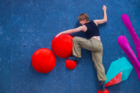 Bouldering climbing athlete woman training at indoor gym boulder climb wall. Teenager fit girl going up having fun in extreme sport hobby. Social media templateの写真素材