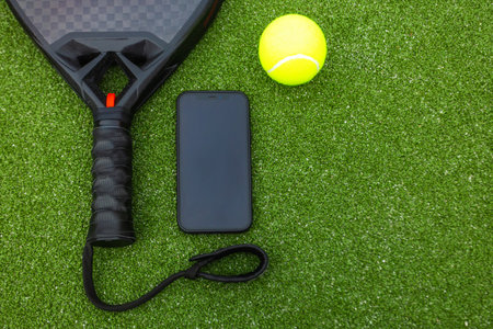 Padel tennis racket and mobile phone. Background with copy space for mobile application. Sport court and ball. Template for design of a sports app or social media advertisementの写真素材