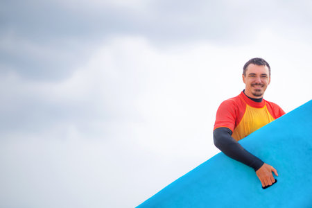 Handsome surfer man near the ocean. Surfing classes. Amateur surfer. Photo for surfing school advertising on social media.の写真素材