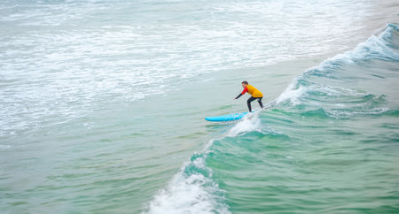 Surfer. Teenage girl learning to surf on foam in the ocean. First surfing lesson. Amateur surfer. Surfing training. Photo for surfing school advertising on social media.の写真素材