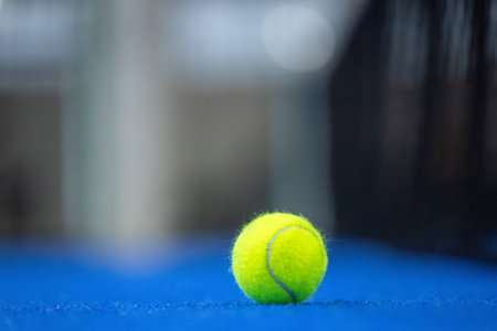 Padel or tennis ball. Background with copy space. Ball at sports court. Social media template. Promotion for padel events.の写真素材
