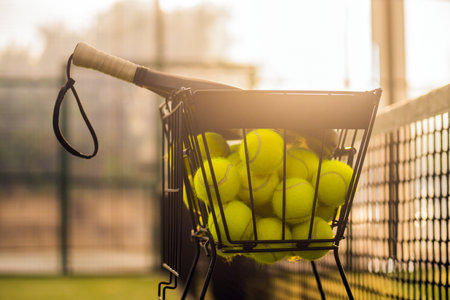 Folding basket with balls for padel classes on the court. Trainer equipment. Background with copy space. Sport court and balls. Background for advertising social padel tournaments and training classesの写真素材