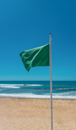 Green Flag on Beach Indicating Safe Swimming Conditions by the Seaの写真素材