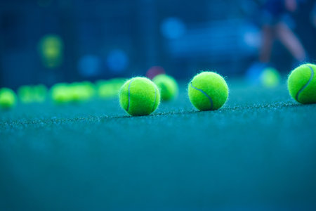 Padel balls on court during sunny day, clean and minimalistic image for sports websites, blogs, and promotional materials.の写真素材