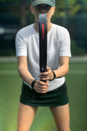 Padel tennis player with racket in action on the court. Woman athlete with paddle racket on court outdoors. Sport concept. Download a high quality photo for the design of a sports app or web site.の写真素材