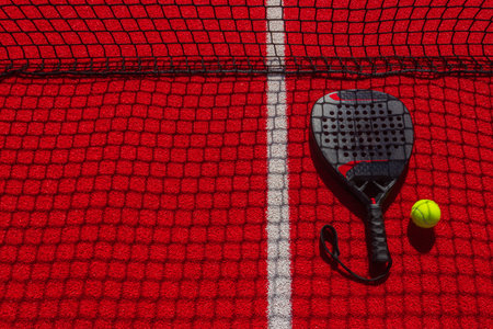 Padel tennis racket with ball. Background with copy space. Red sports court and balls. Download a...