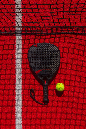 Padel tennis racket with ball. Background with copy space. Red sports court and balls. Download a high quality photo with paddle for the design of a sports app or social media advertisementの写真素材