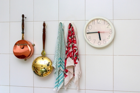 kitchen utensils and wall clock hanging on a white tiled wallの写真素材