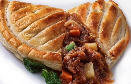 meat pie displaying sauce, meat, and vegetablesの写真素材
