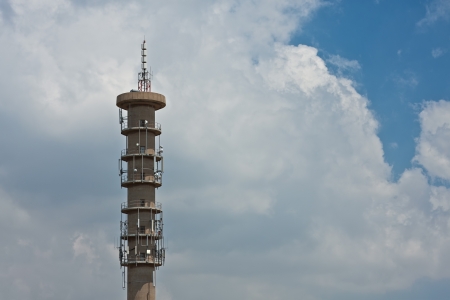 concrete radio and digital telecommunications tower exterior against a clouded sky backgroundの写真素材