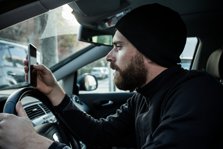 Man using his phone and drivingの写真素材