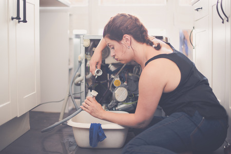 Woman trying to repair the washing machineの写真素材