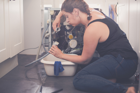 Woman trying to repair the washing machineの写真素材