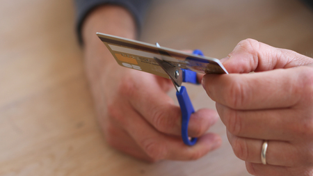 Man cutting his credit card with scissorsの写真素材