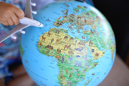Travel concept children play airplane on earth globeの写真素材