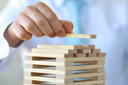 Businessman builds a tower with a wooden brigの写真素材