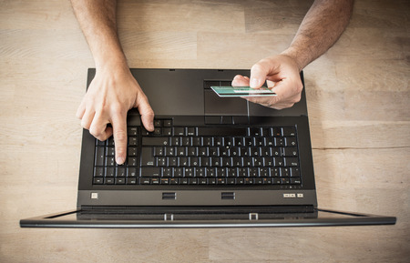 Man shopping online using laptop with credit cardの写真素材