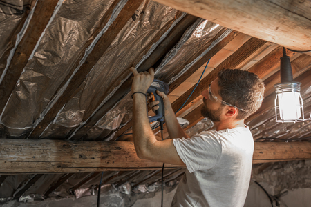 Man makes thermal insulation of the attic of the houseの写真素材