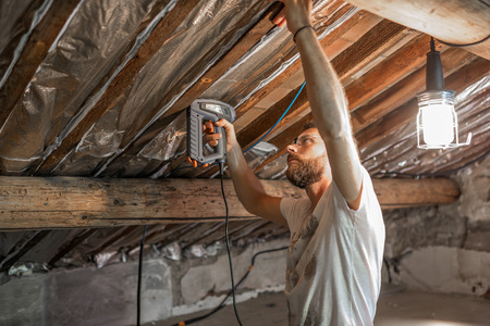 Man makes thermal insulation of the attic of the houseの写真素材