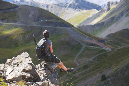 Hiker with backpack relaxing on top of mountains and enjoying the view - Mixed colorの写真素材