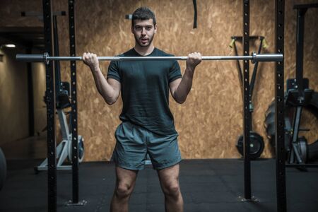Attractive man doing heavy barbell workout and lifting