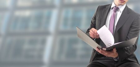 businessman seated works on folder in binderの写真素材