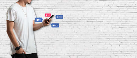Social media concept - Banner with young man holding smartphone and with social media iconの写真素材