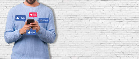 Social media concept - Banner with young man holding smartphone and with social media iconの写真素材