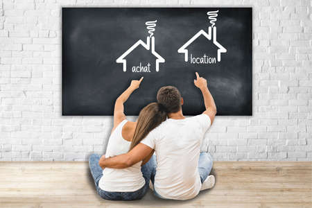 The couple sit on the floor and gesture to the wall with a virtual houseの写真素材