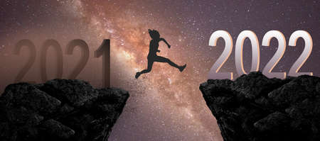 Silhouette man or woman jumping between year 2021 to year 2022 years. Concept of a better yearの写真素材