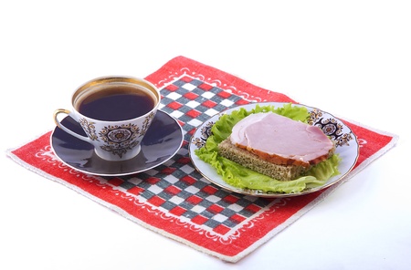 A cup of coffee and a plate with a sandwich on a red napkin. White backgroundの写真素材