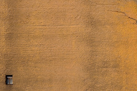 A wall with a small window and a crackの写真素材