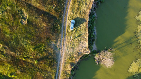 the car is driving along the road through the meadows and fields shooting from a drone, Ukraineの写真素材