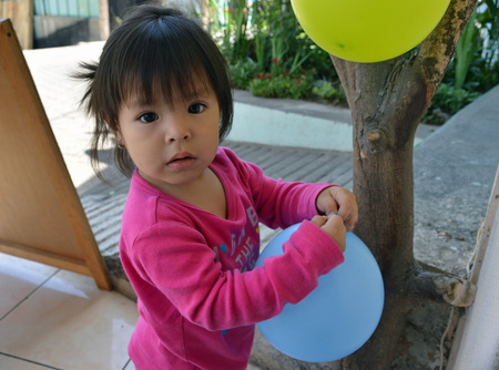 SAN PEDRO, GUATEMALA - JULY 2, 2015; An unknown Guatemalan child plays with ballons outside her families coffee shop.のeditorial素材