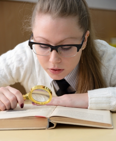 woman reading a book with a magnifying glassの写真素材