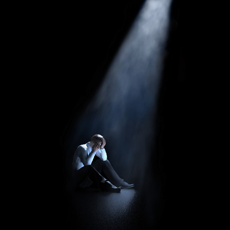 lonely man sitting in a dark roomの写真素材