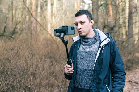 Male tourist uses stabilizer for phone and shoots natureの写真素材