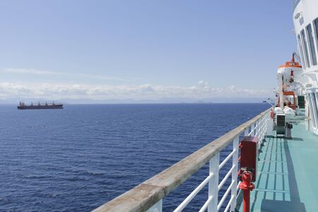 The long deck of the ship, beautiful scenery and a huge tanker drifting into the sea.