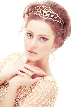 Young shy woman in a diadem of gold, isolated on white background.の写真素材