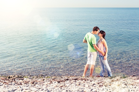 Young lovers kissing near water, lens flaresの写真素材