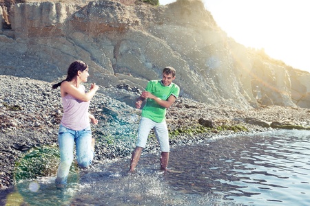 Couple playing in water on the beach, splashes, sunbeams and lens flares, motion blurの写真素材