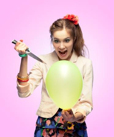 Crazy girl is going to pop a balloon with a knifeの写真素材