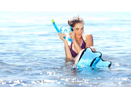 Beautiful tanned girl with snorkeling equipment resting in shallow waterの写真素材