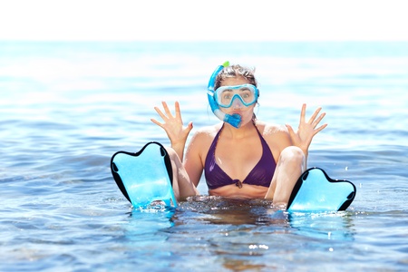 Beautiful tanned girl with snorkeling equipment having fun in shallow waterの写真素材