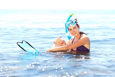 Beautiful tanned girl with snorkeling equipment resting in shallow waterの写真素材