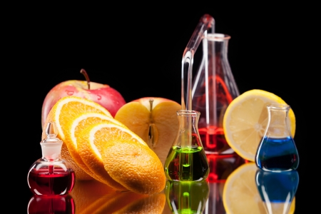 Still life of laboratory glassware with colorful liquids and fruits on black backgroundの写真素材